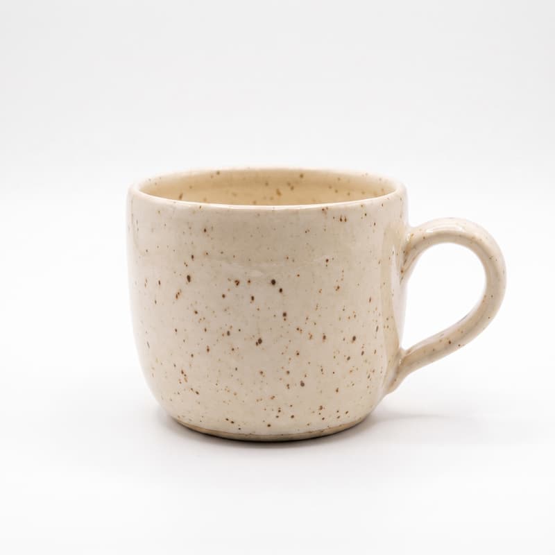 Eine gesprenkelte Keramiktasse auf einem weißen Hintergrund