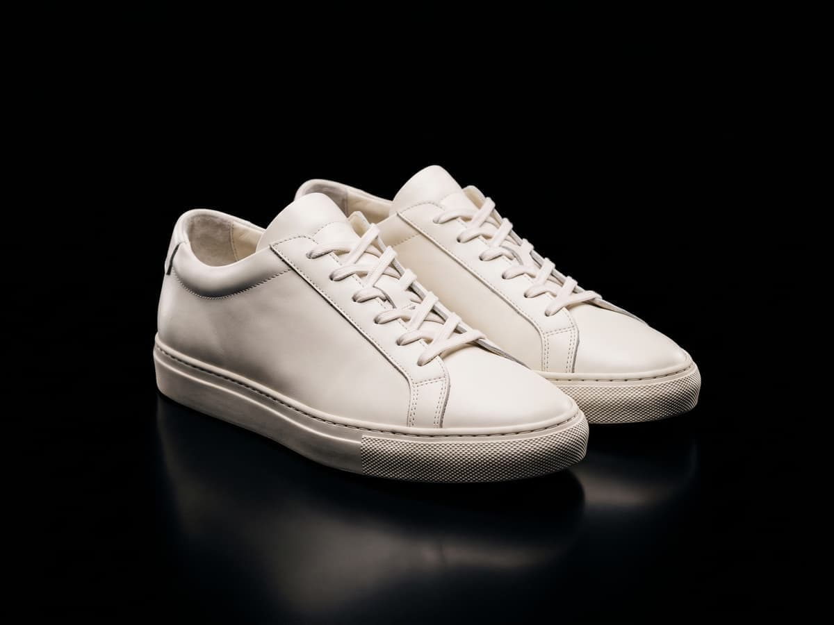 Dieselben weißen Sneaker auf einem reinen schwarzen Hintergrund
