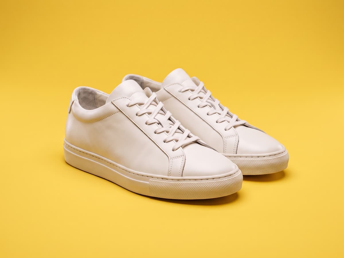 Weiße Ledersneaker auf einem leuchtend gelben Hintergrund
