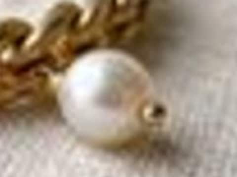 Close detail of the pearl charm and chain links, blurry and smeared